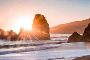 "god rays" over a sunrise on a beach reimagining Christianity