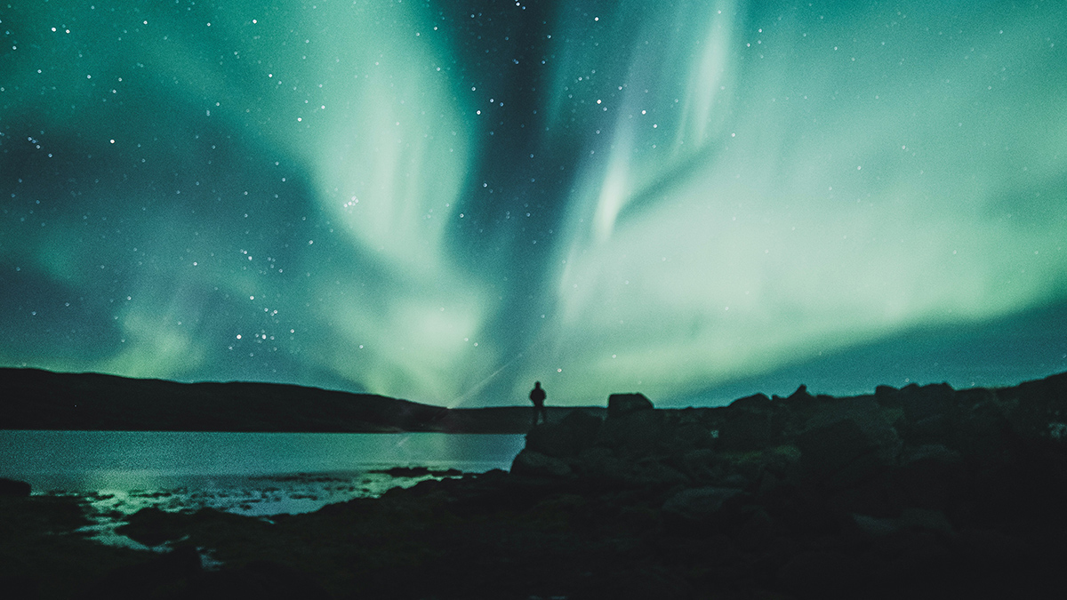 a person standing under the aurora